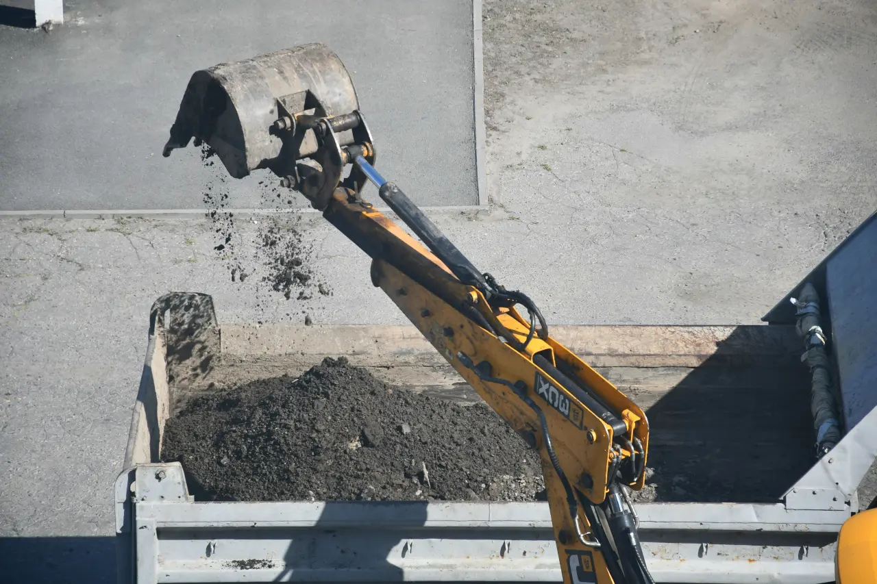Excavator dropping rocks to a truck